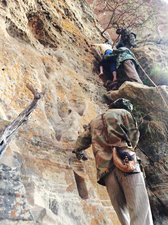 Locals helping tourists climb a 10m vertical wall